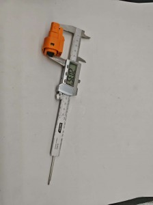 The inspector uses a vernier caliper to measure a high voltage connector